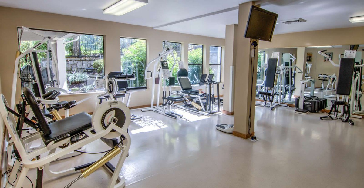 A bright gym room equipped with various fitness machines.