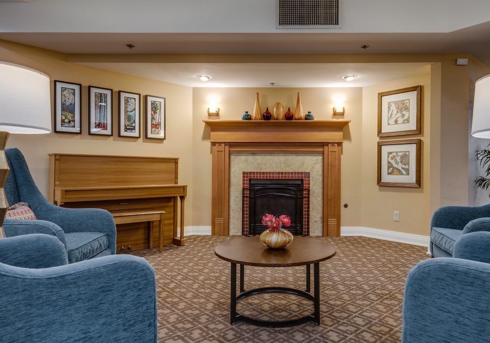 A cozy living room interior with a fireplace, piano, and seating area.