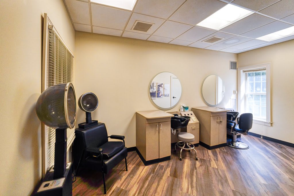 A well-equipped beauty salon interior with chairs, mirrors, and a hair dryer.