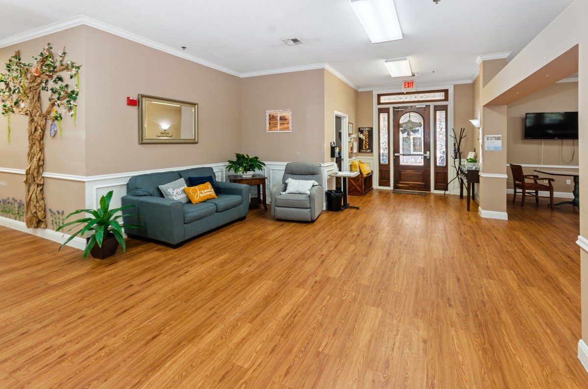 A cozy living area with a couch, armchair, and wooden flooring.