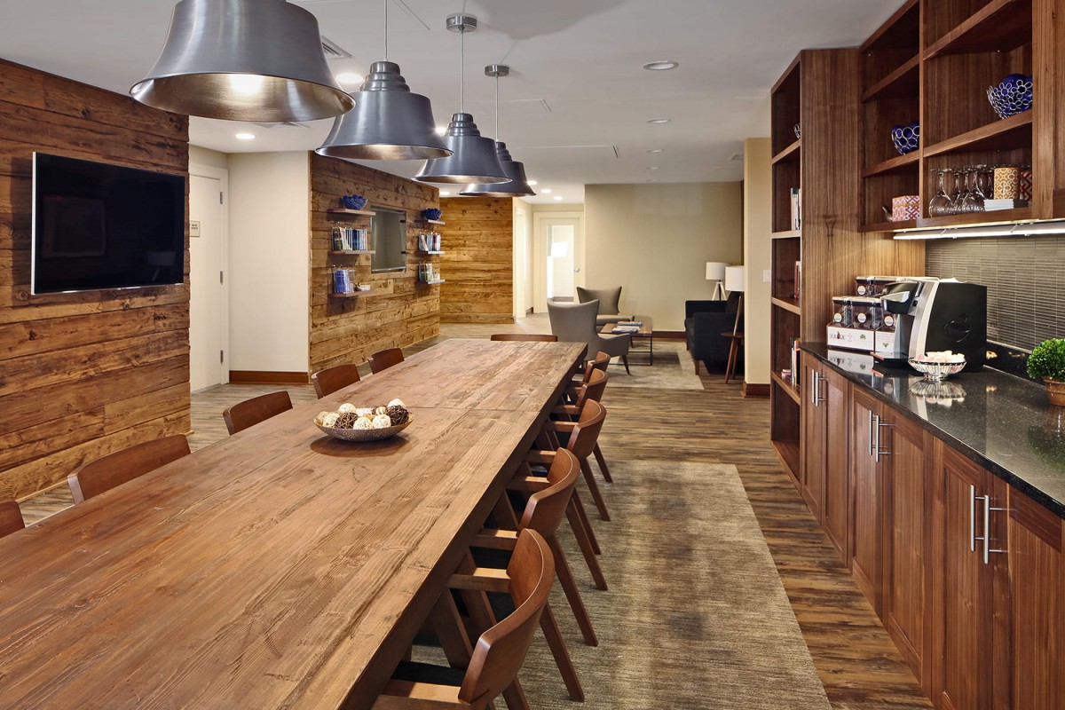 A modern dining area with a long wooden table and industrial lighting.