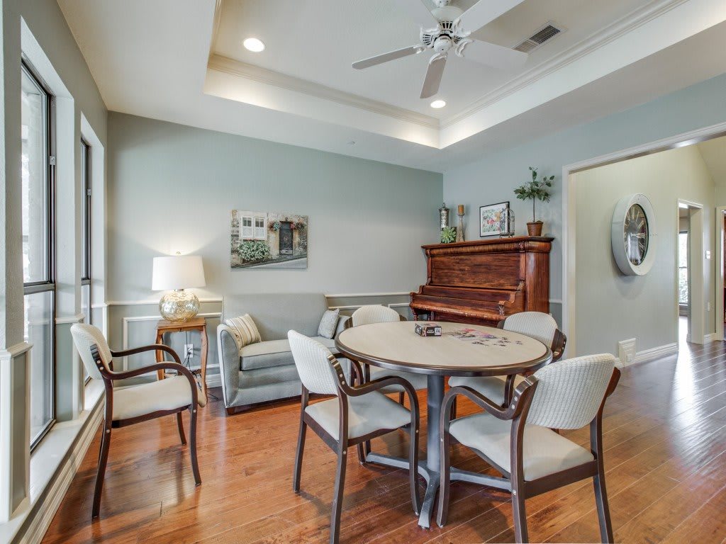 A cozy living room with a wooden piano, round table, and comfortable seating.