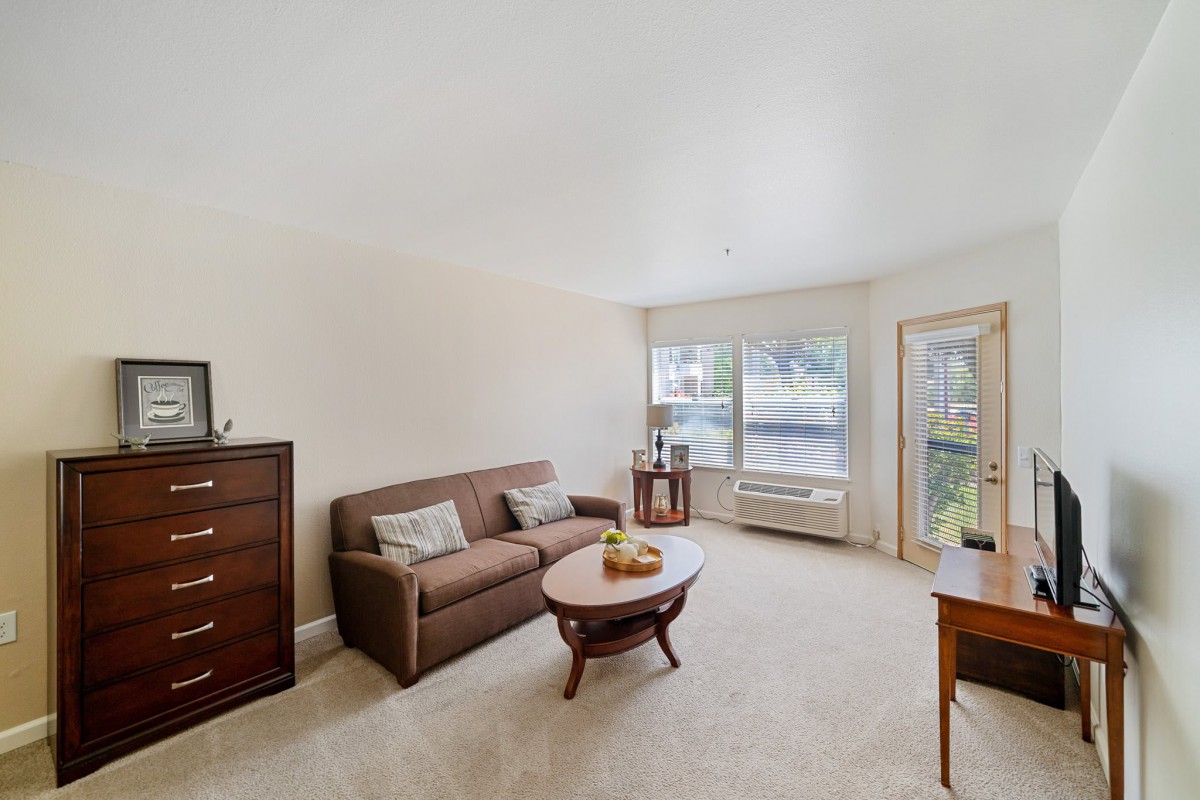 A cozy living room with a sofa, coffee table, and large window.