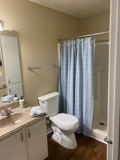 A small bathroom featuring a toilet, shower with a blue curtain, and a vanity with a sink and mirror.