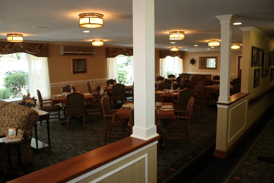 A cozy dining room with tables and chairs arranged neatly under warm lighting.