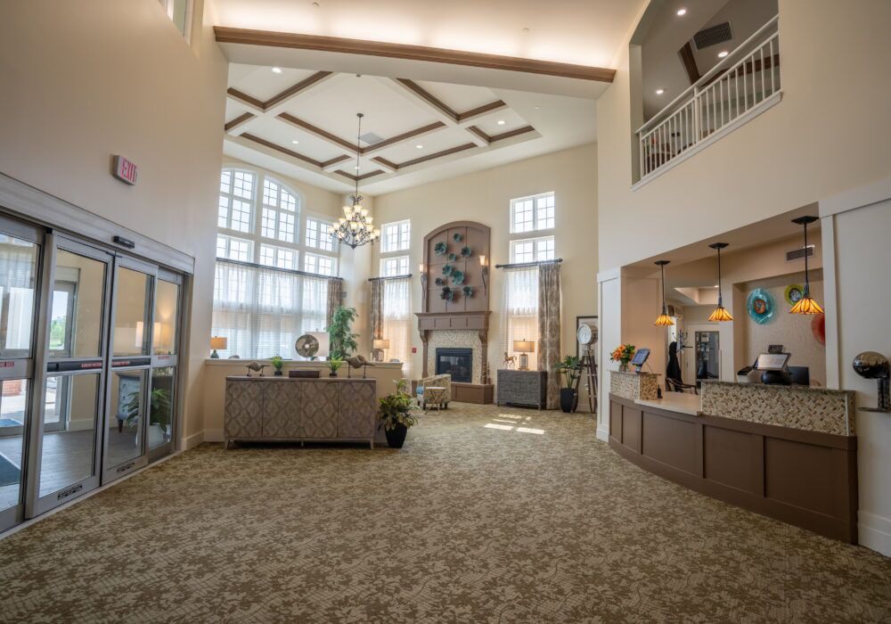 A spacious lobby featuring large windows, a chandelier, and a reception desk.