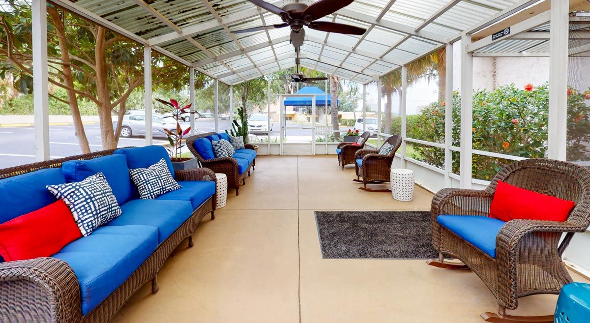 A cozy outdoor patio with blue-cushioned seating and a ceiling fan.