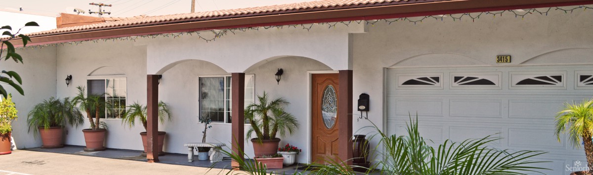 A cozy house entryway featuring a wooden door, potted plants, and arched porch design.