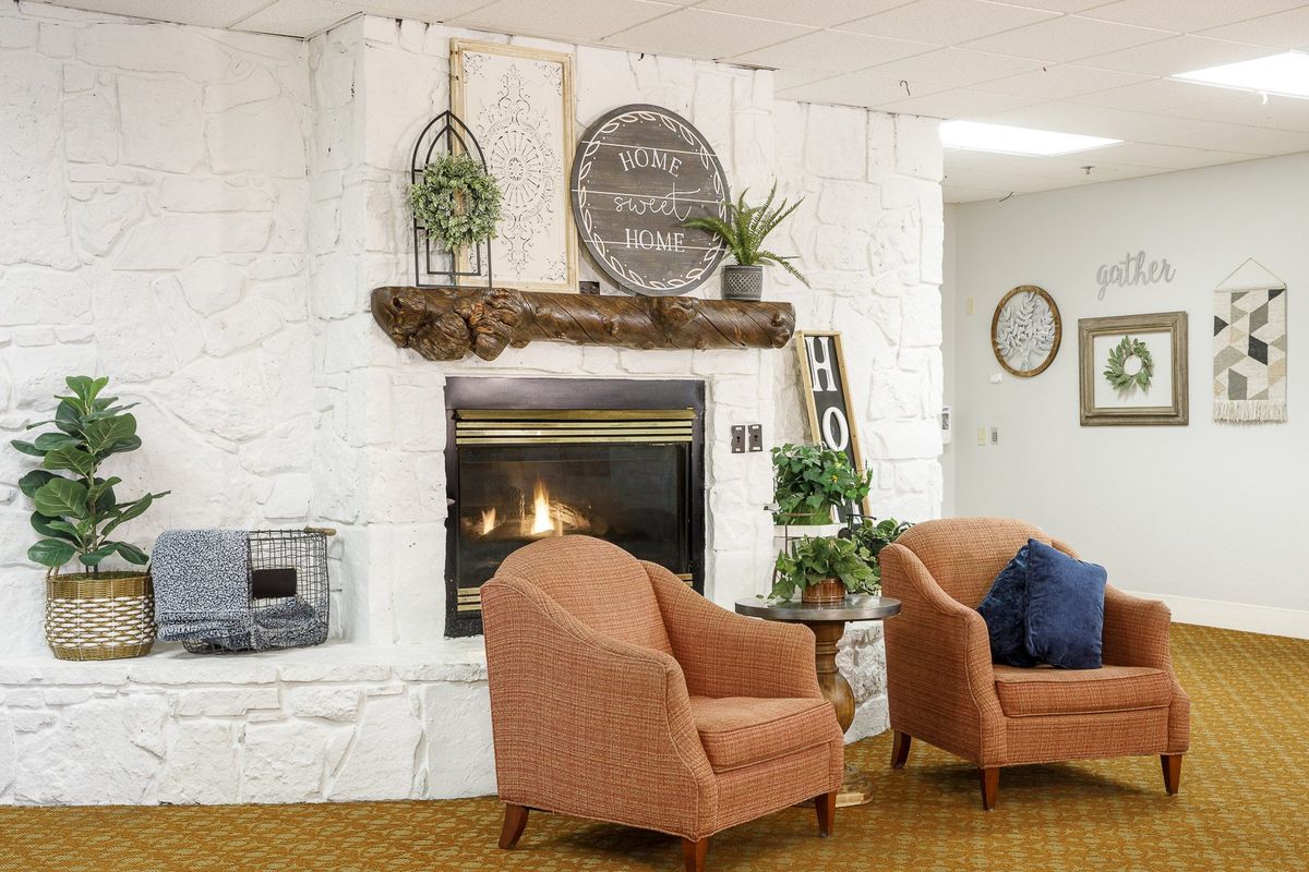 A cozy living room featuring a fireplace, comfortable armchairs, and decorative elements that create a warm atmosphere.