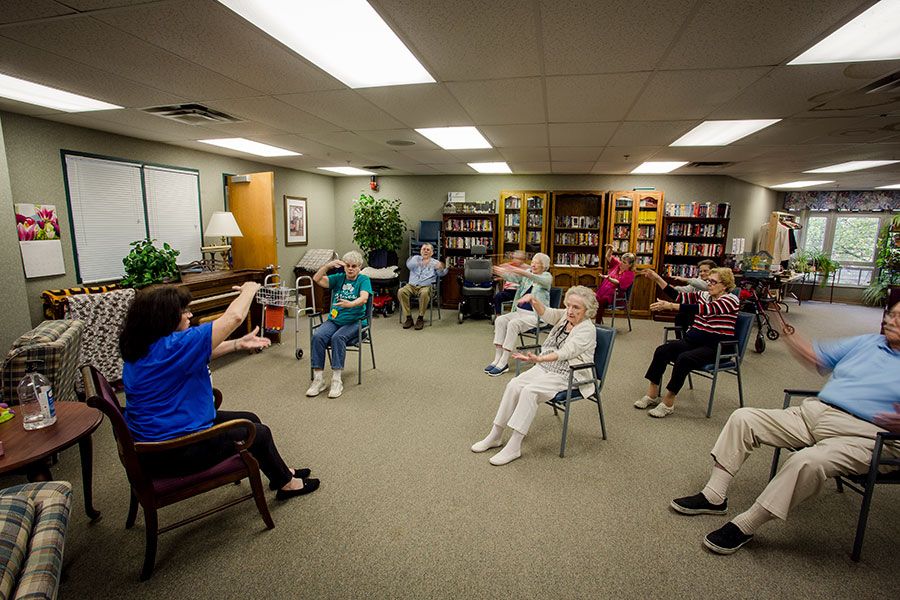 A group of seniors participating in a chair yoga session at a community center.