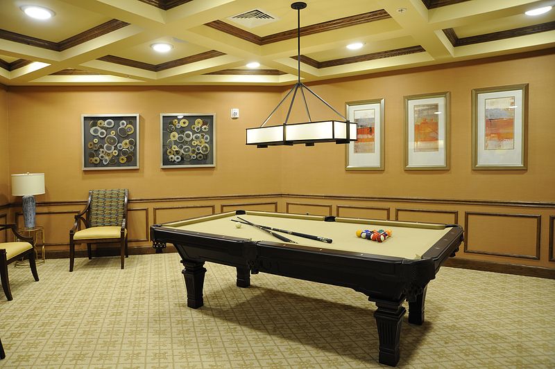 A cozy game room featuring a pool table under warm lighting, accented by framed artwork on the walls.