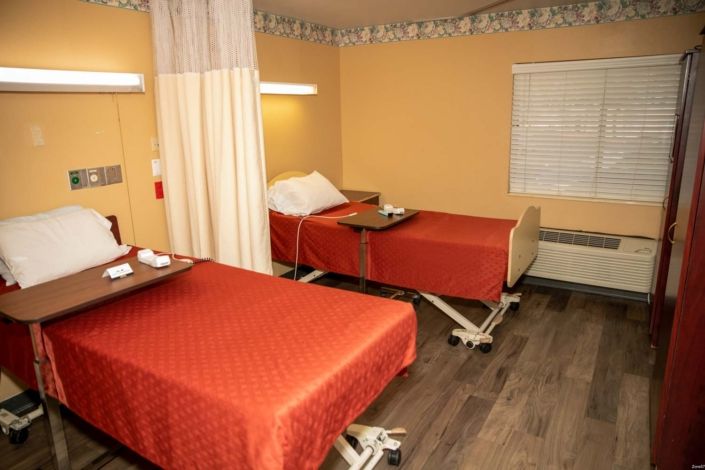 Hospital room with two beds separated by a curtain.
