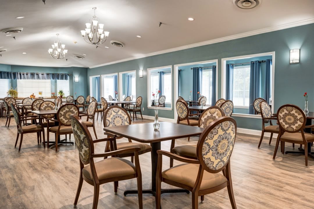 Elegant dining room with neatly arranged tables and chairs, featuring stylish lighting fixtures and large windows.