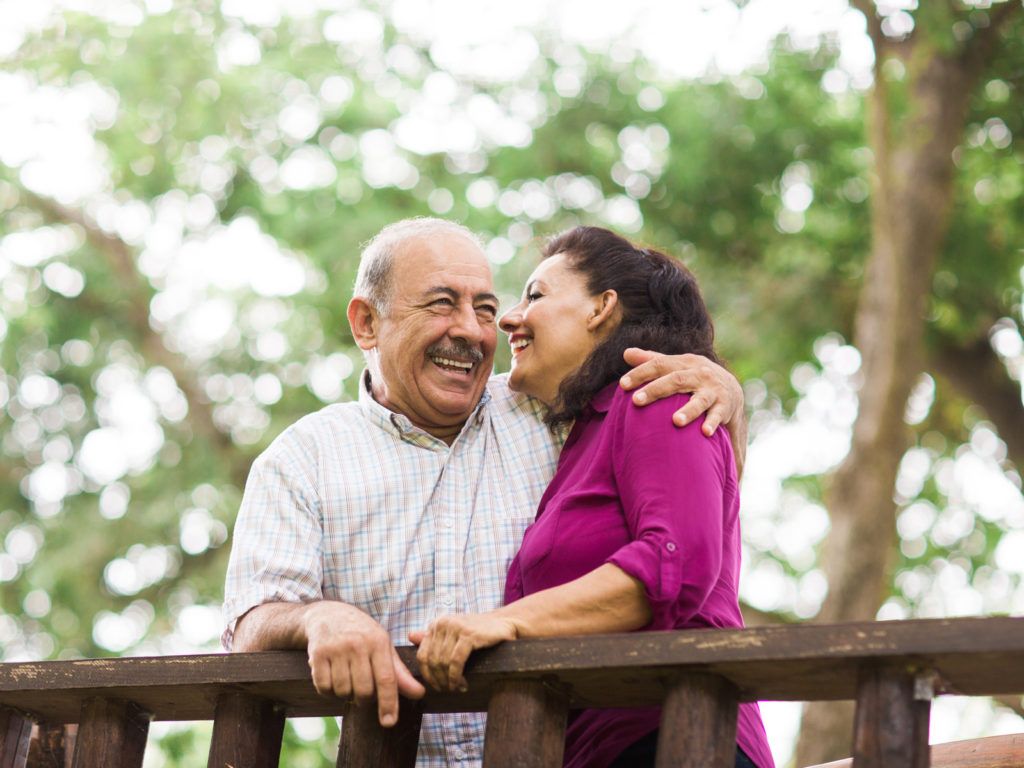A joyful couple embracing on a wooden bridge surrounded by trees.