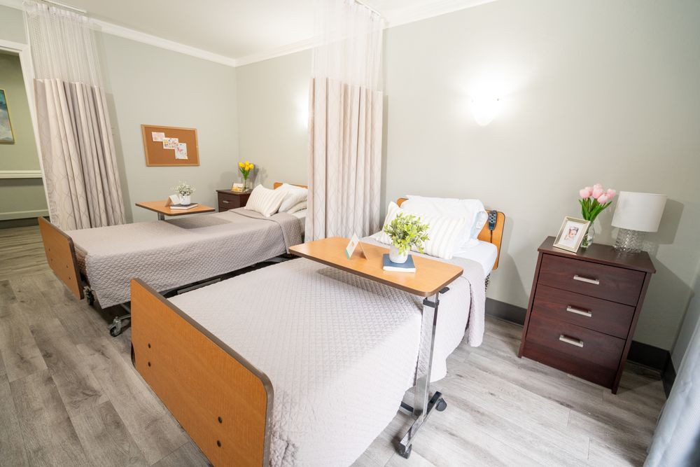 A clean and organized hospital room with two patient beds separated by a curtain.