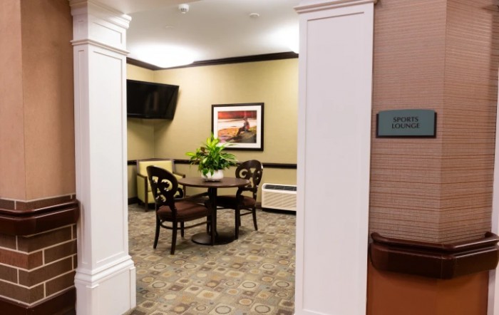 A cozy waiting area with a small table, two chairs, and decorative elements such as a painting and a television.
