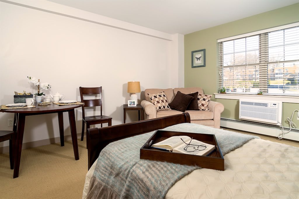 A cozy bedroom with a bed, sofa, and table setup in a neatly decorated space.