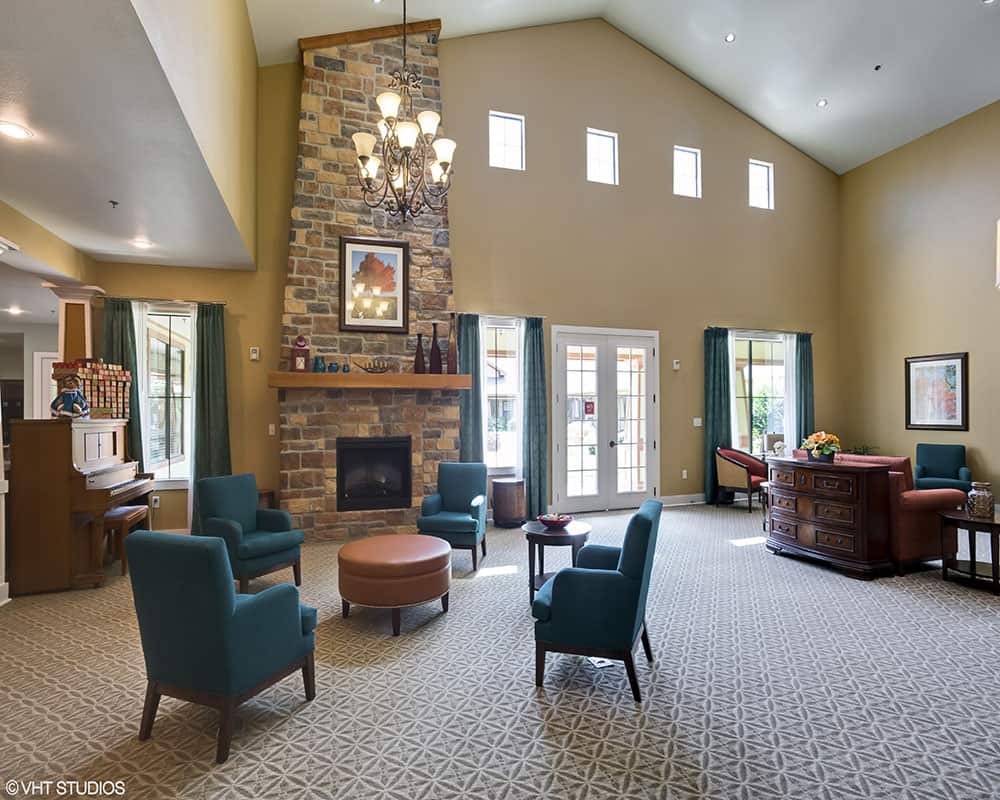 A spacious living room with high ceilings, featuring a stone fireplace and elegant furniture.