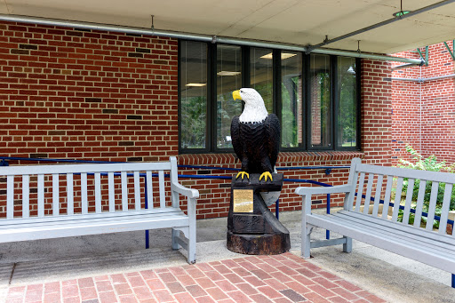 A bold eagle statue stands proudly between two benches on a brick patio.