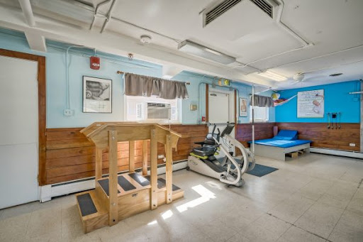 A bright and spacious gym area featuring exercise equipment and a wooden platform.
