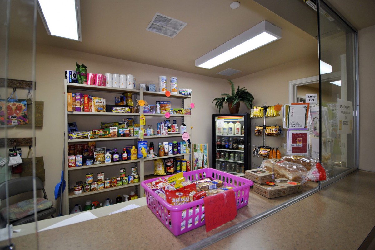 A small grocery store with shelves stocked with various products and a basket on the counter.
