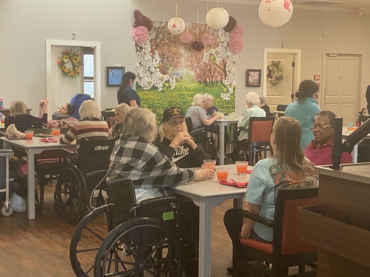 A group of elderly individuals in a nursing home, some in wheelchairs, enjoying a social activity together.
