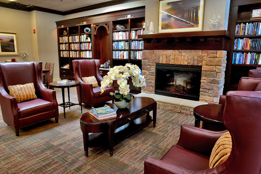 A cozy lobby area featuring comfortable chairs, a welcoming fireplace, and bookshelves filled with books.