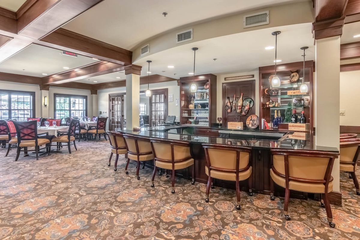 A spacious and elegant bar area with upholstered seating and warm lighting.