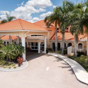 A beautiful tropical building with a red-tiled roof and palm trees at the entrance.