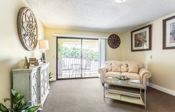 A cozy living room with a sofa, coffee table, and sliding glass door leading to an outdoor area.