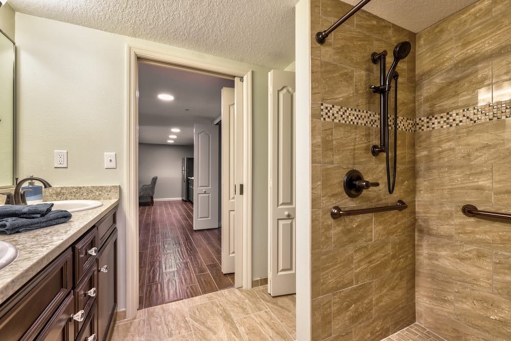 Modern bathroom with a tiled shower and adjacent living area.