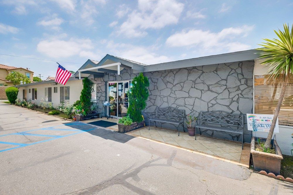 A building entrance with a stone facade, adorned by an American flag and flanked by benches.