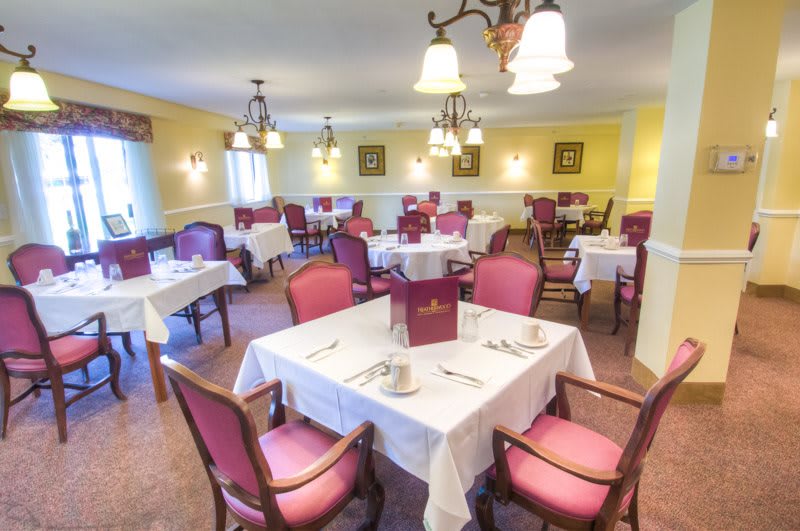 An elegant dining room with neatly arranged tables and chairs, set for a meal.
