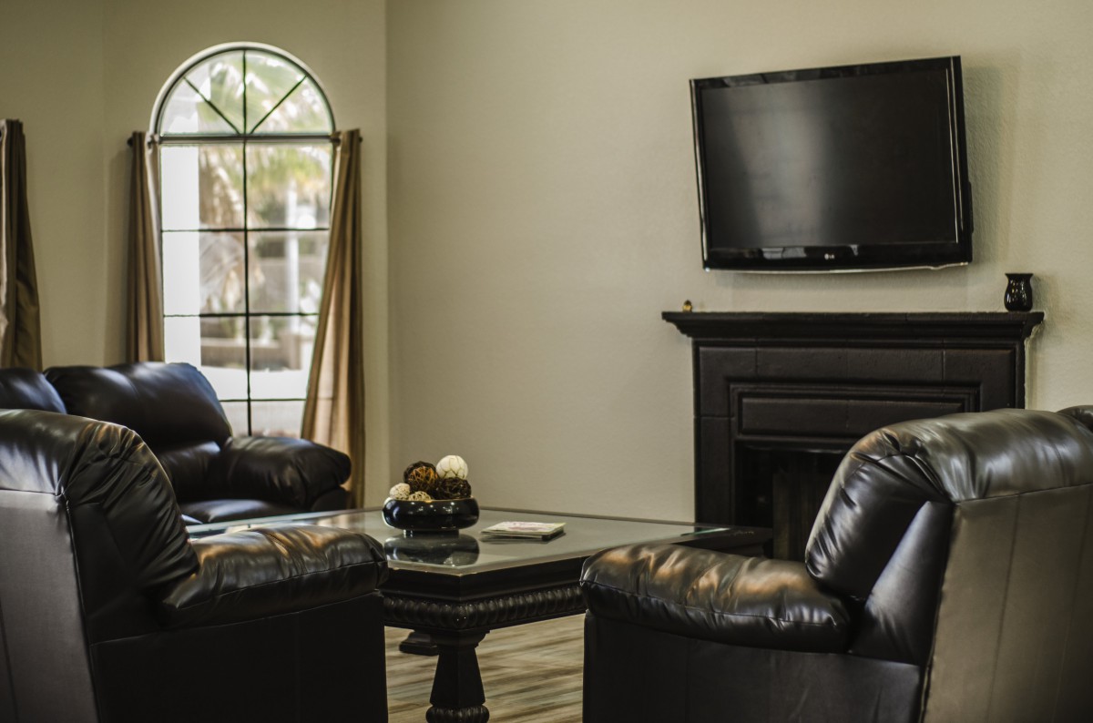 A cozy living room with leather chairs, a fireplace, and a mounted television.