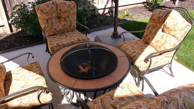 A cozy outdoor patio setup featuring a firepit surrounded by cushioned chairs, perfect for gatherings.