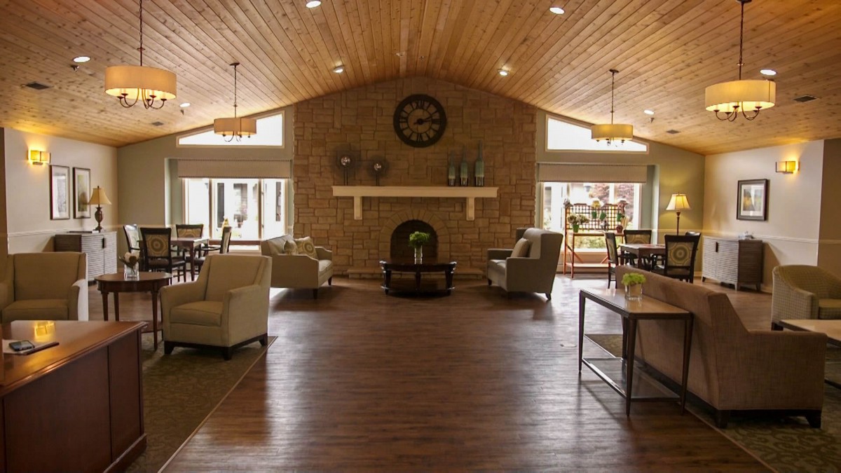 A cozy living room with a wood ceiling, featuring a central fireplace and comfortable seating.