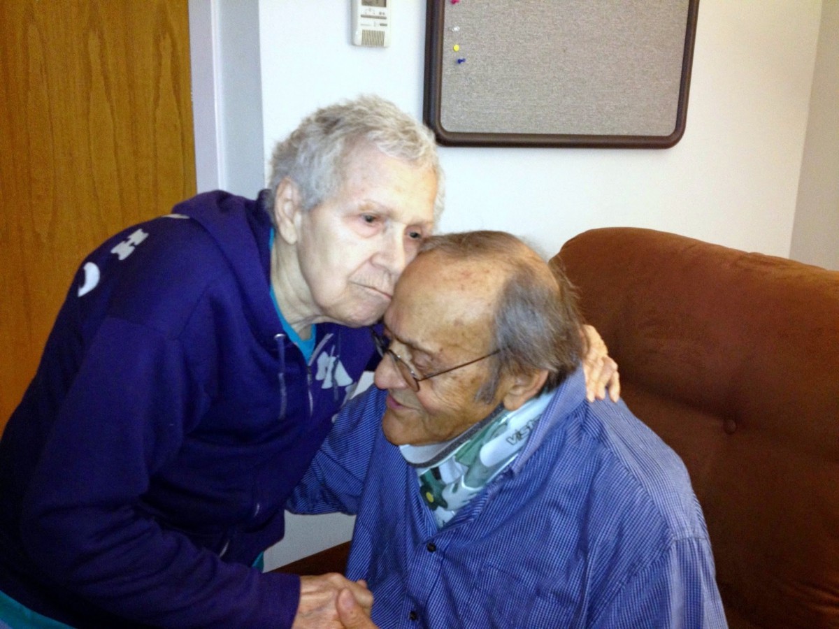 An affectionate moment shared between two elderly individuals indoors.