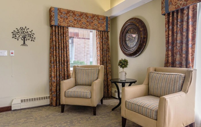 A cozy living room with two armchairs, a side table, and decorative curtains.