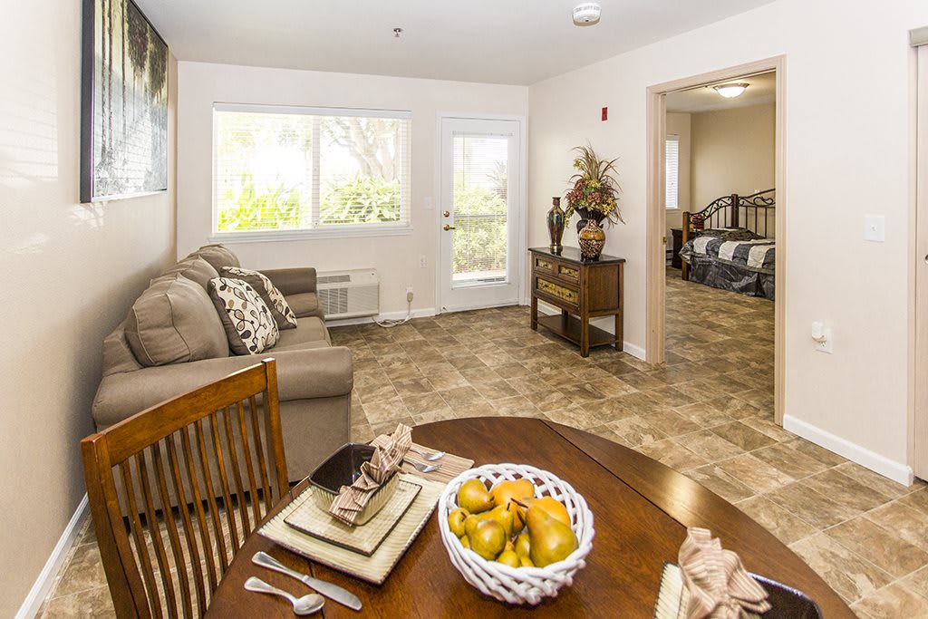 A cozy apartment living area with a dining table and a view into the bedroom.