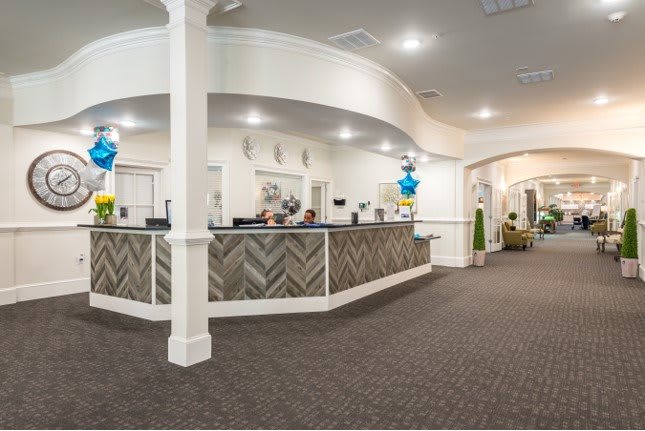 A modern reception area with a stylish, herringbone-patterned front desk and decorative balloons.