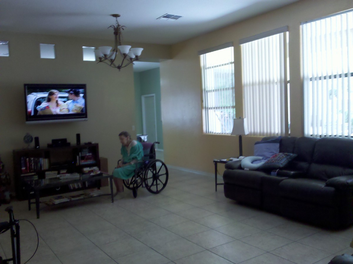 A person in a wheelchair watching TV in a living room.