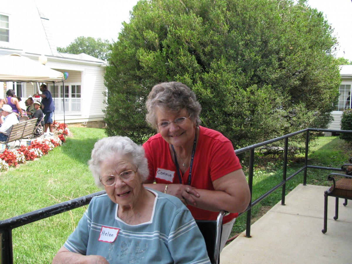 Two women enjoying a sunny day in the garden, with one seated in a wheelchair.