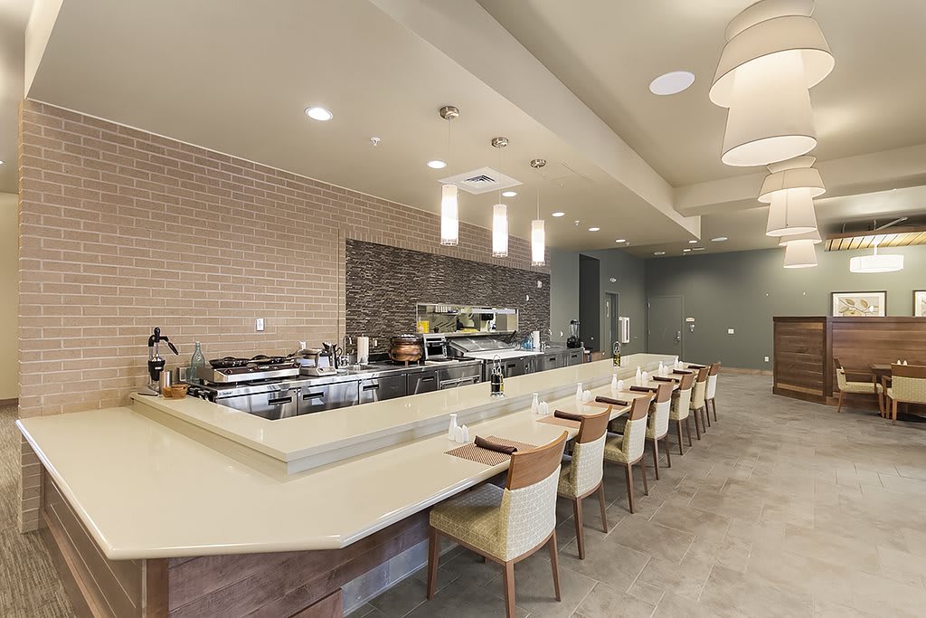 A modern restaurant interior featuring a long bar counter with seating and contemporary lighting.