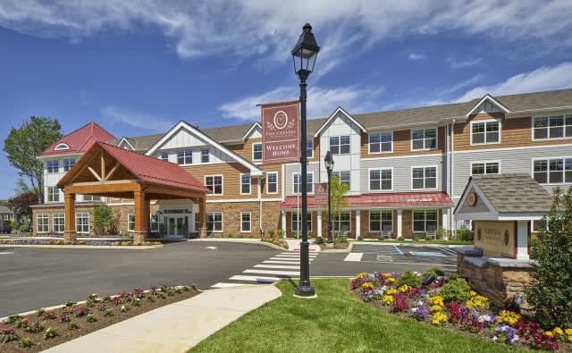 A modern residential building with well-maintained landscaping and a partly cloudy sky.