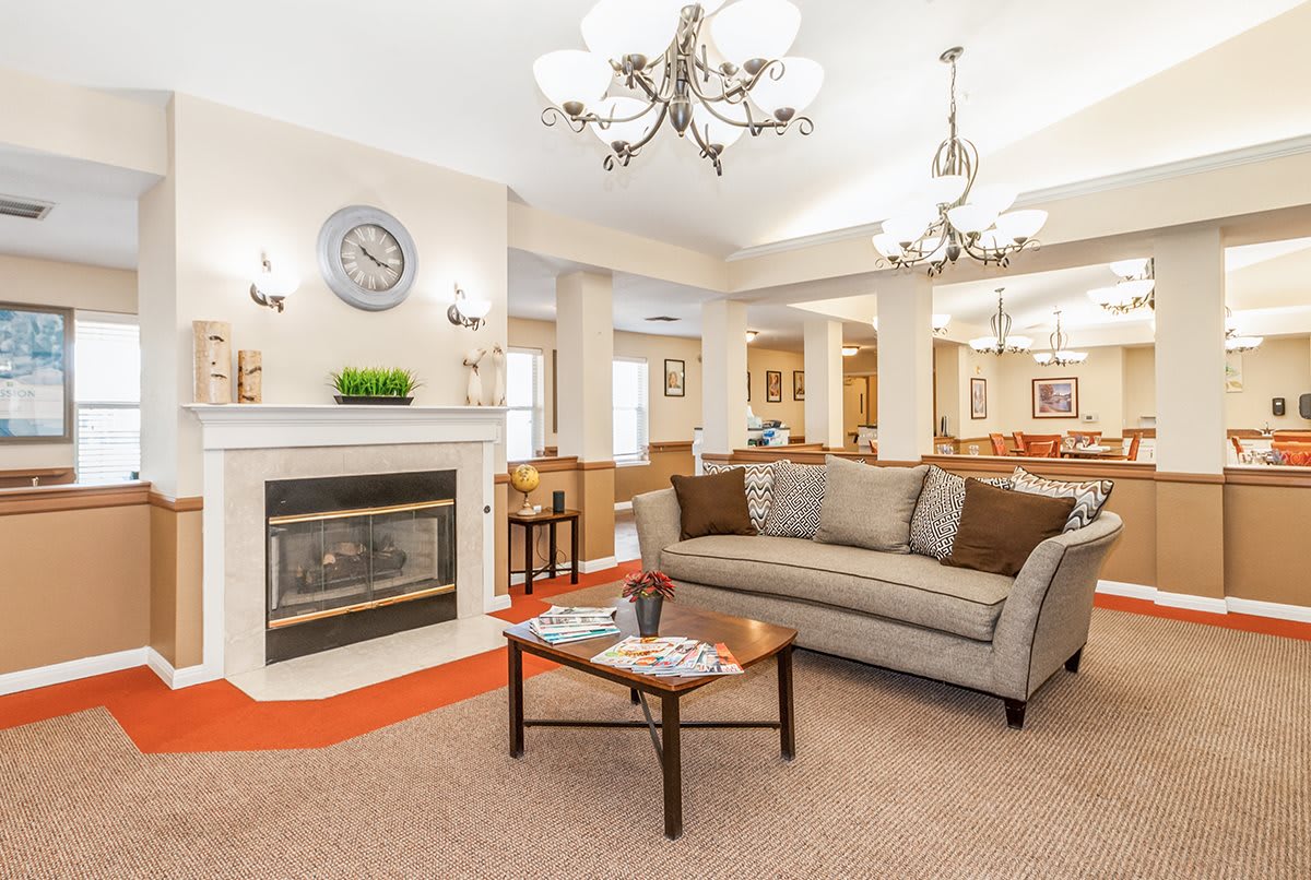 A cozy and elegant living room with a fireplace, comfy sofa, and stylish chandeliers.