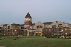 A large brick building on a university campus with a tower and illuminated entrance.