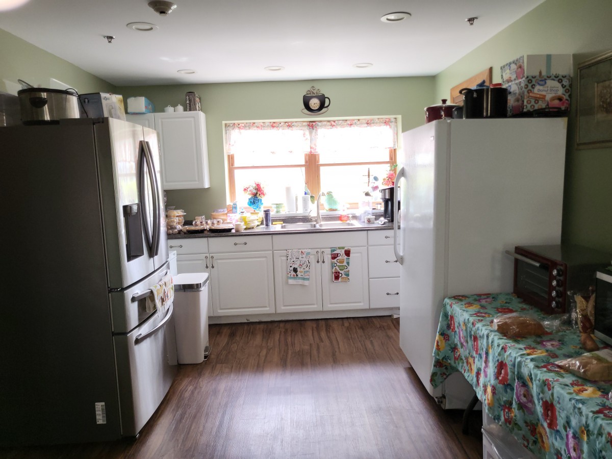A bright kitchen with modern appliances and a wooden floor.