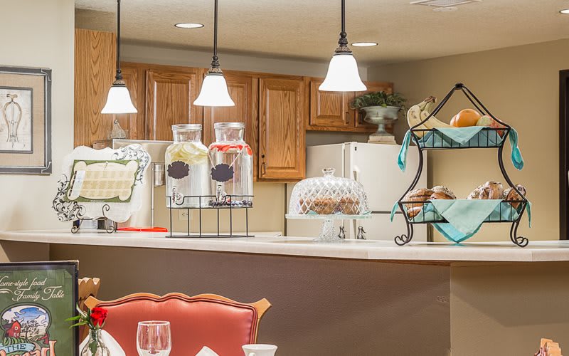 A cozy kitchen interior with wooden cabinets, decorative lighting, and a variety of countertop items.