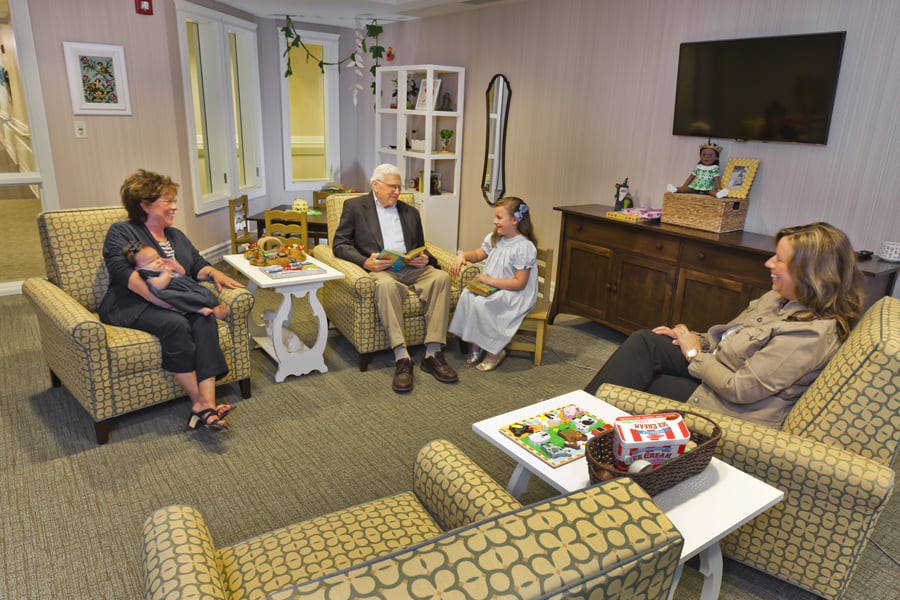 A group of people engaged in a conversation in an office seating area.