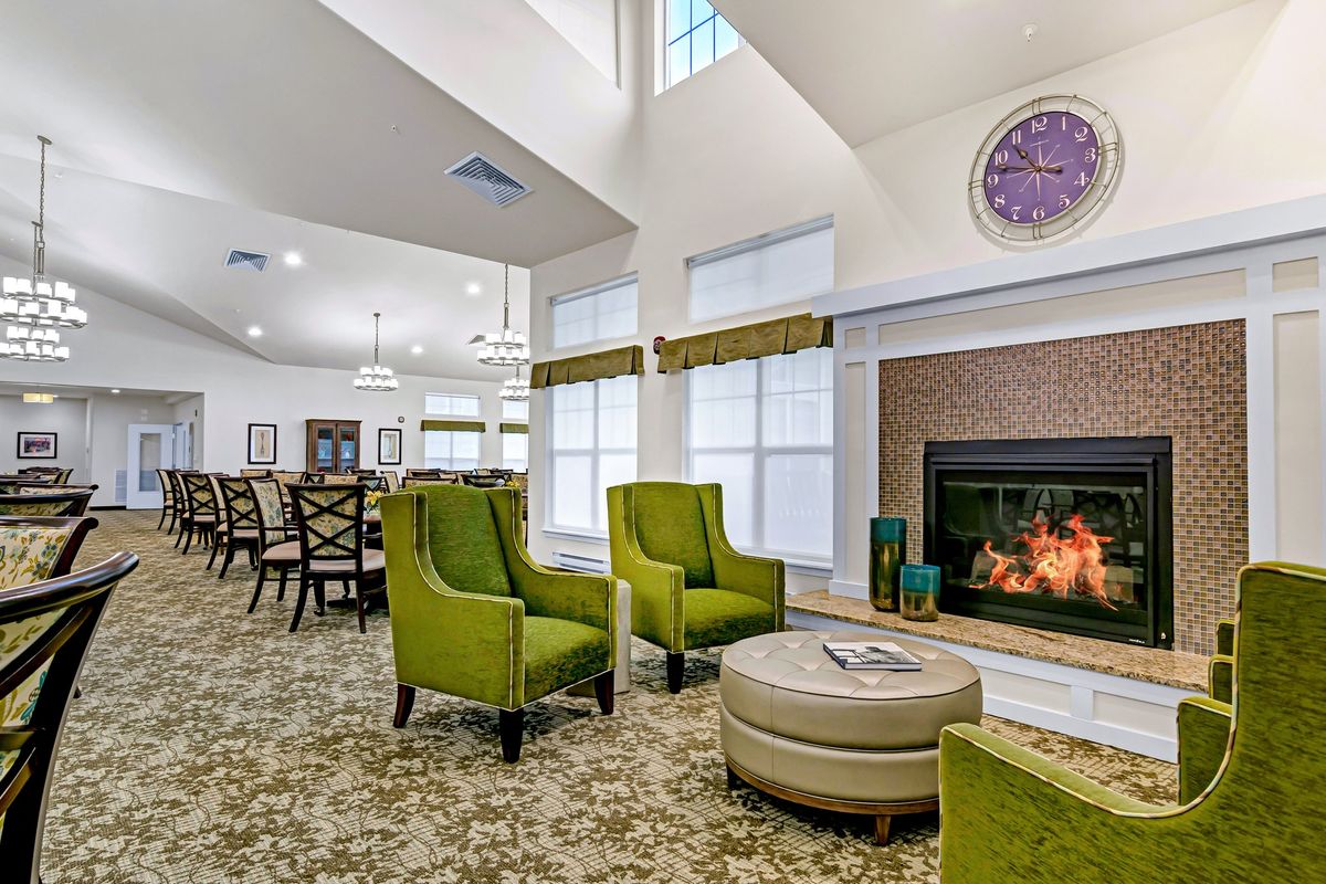 A modern living room with green chairs and a fireplace, featuring cozy and stylish decor.